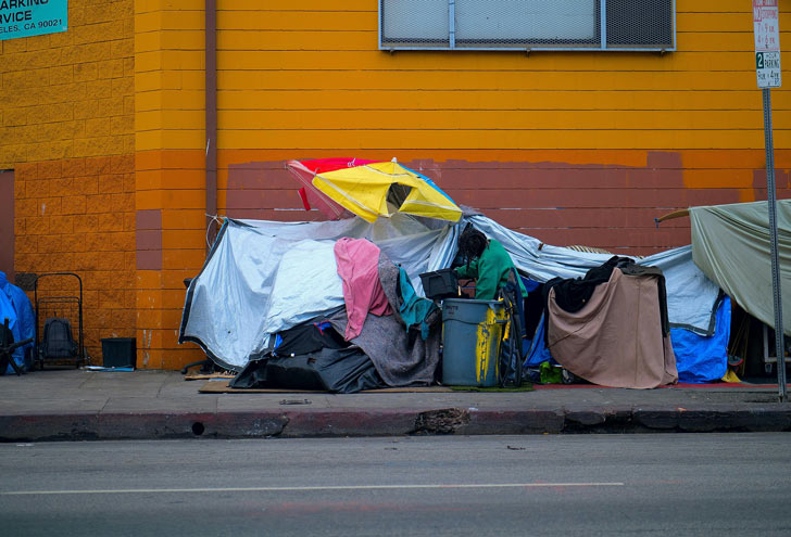 A homelessness encampment in front of an orange building