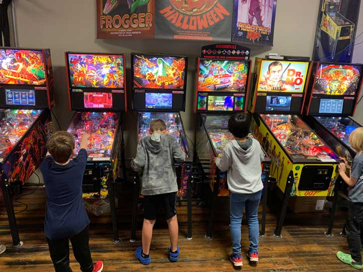 Four young boys play games in a pinball arcade