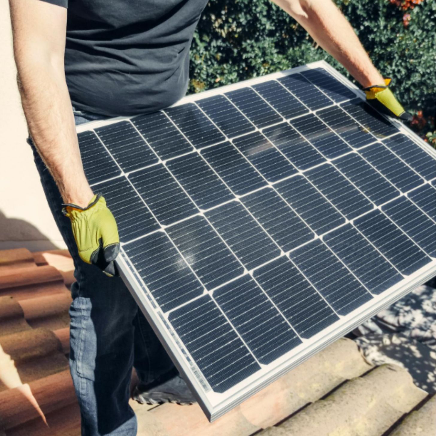 A man with gloved hands holds up a solar panel
