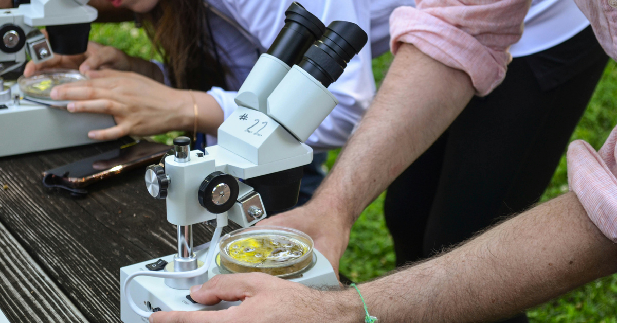 A close-up of a person touching a microscope