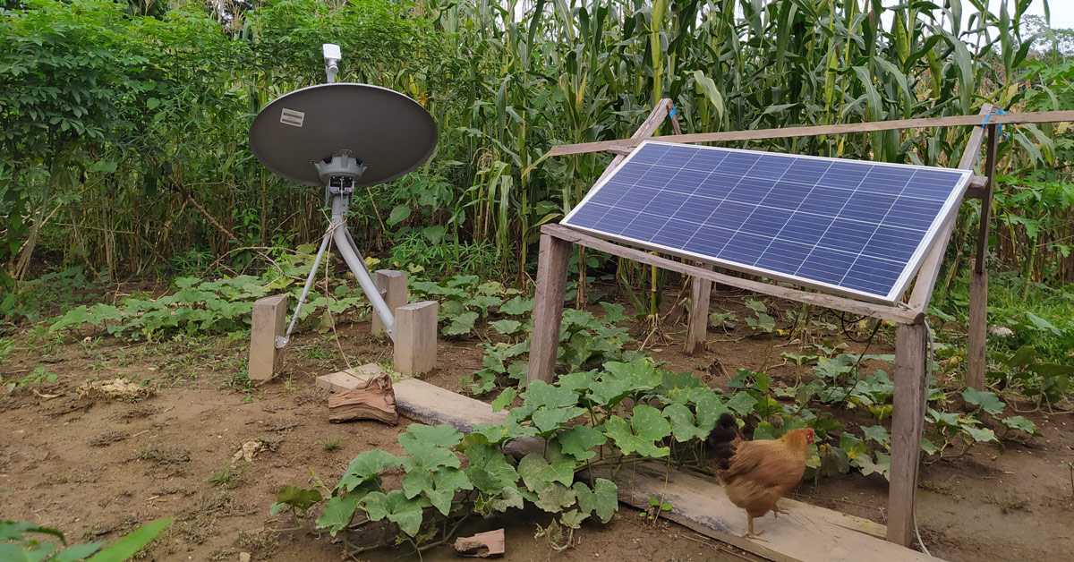A solar panel on wooden stilts sits in a remote farm area