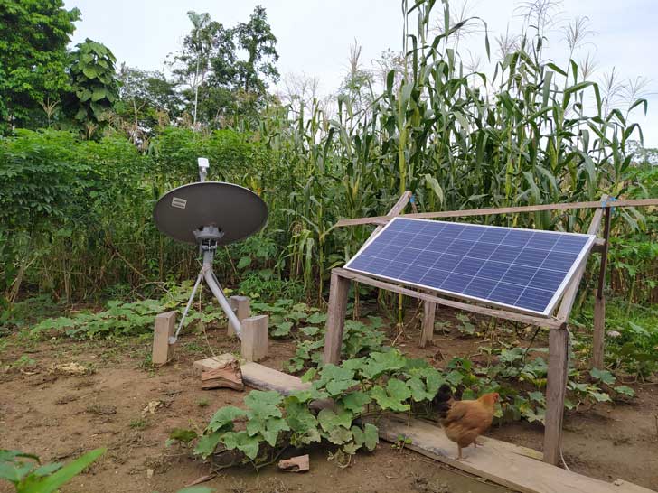 A solar panel on wooden stilts sits in a remote farm area
