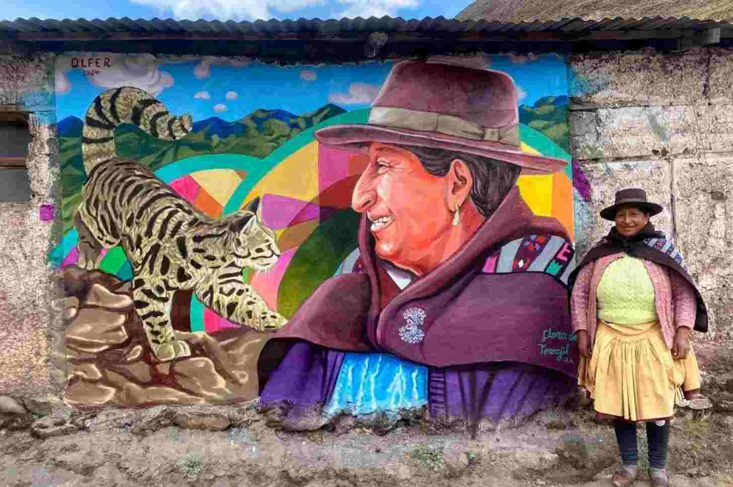 Licapa resident Alicia Ccaico stands alongside a mural featuring her likeness and an Andean cat. Image courtesy of Mujeres Quechua por la Conservación.
