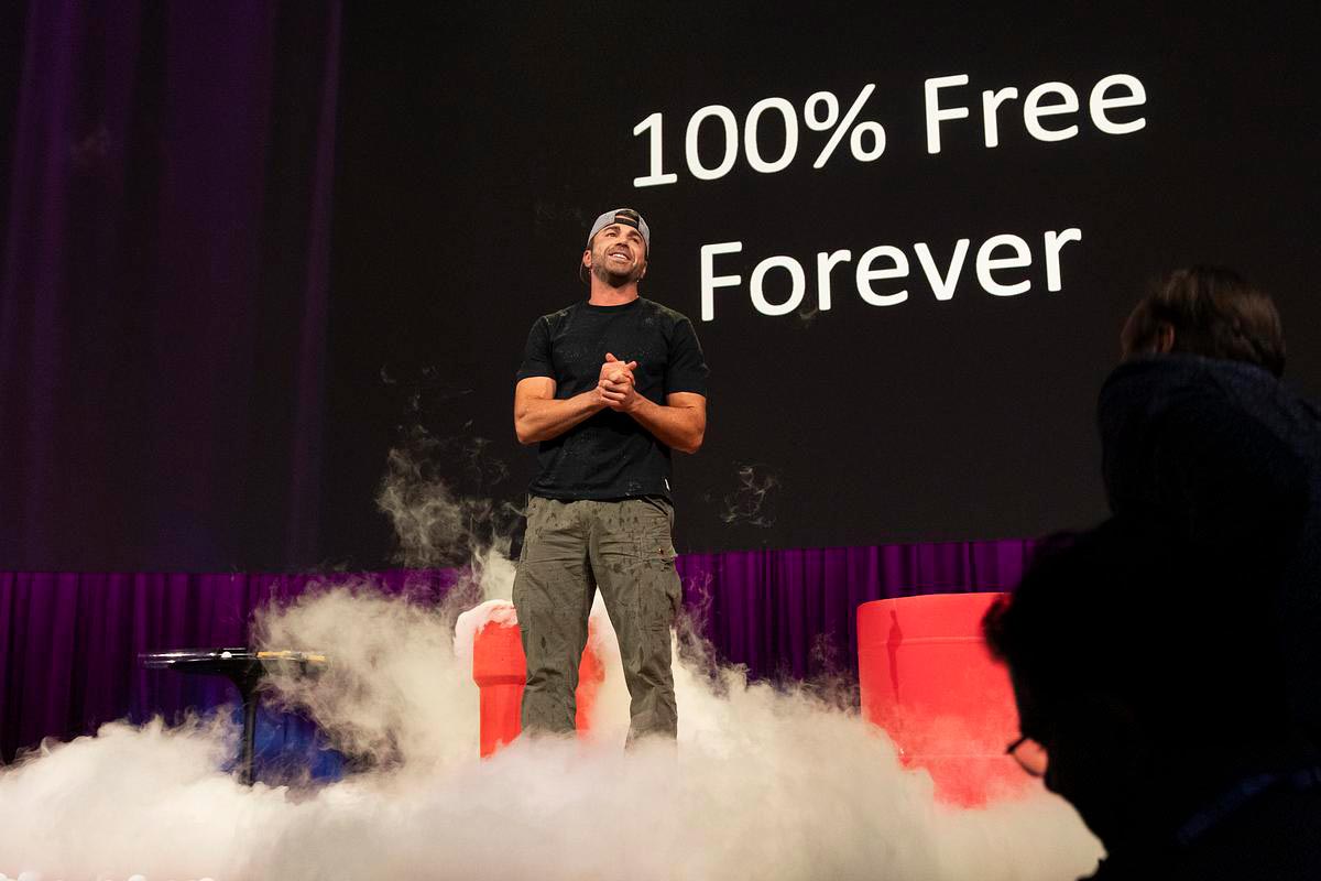 Mark Rober speaks on the TED stage in front of a screen that reads "100% Free Forever"