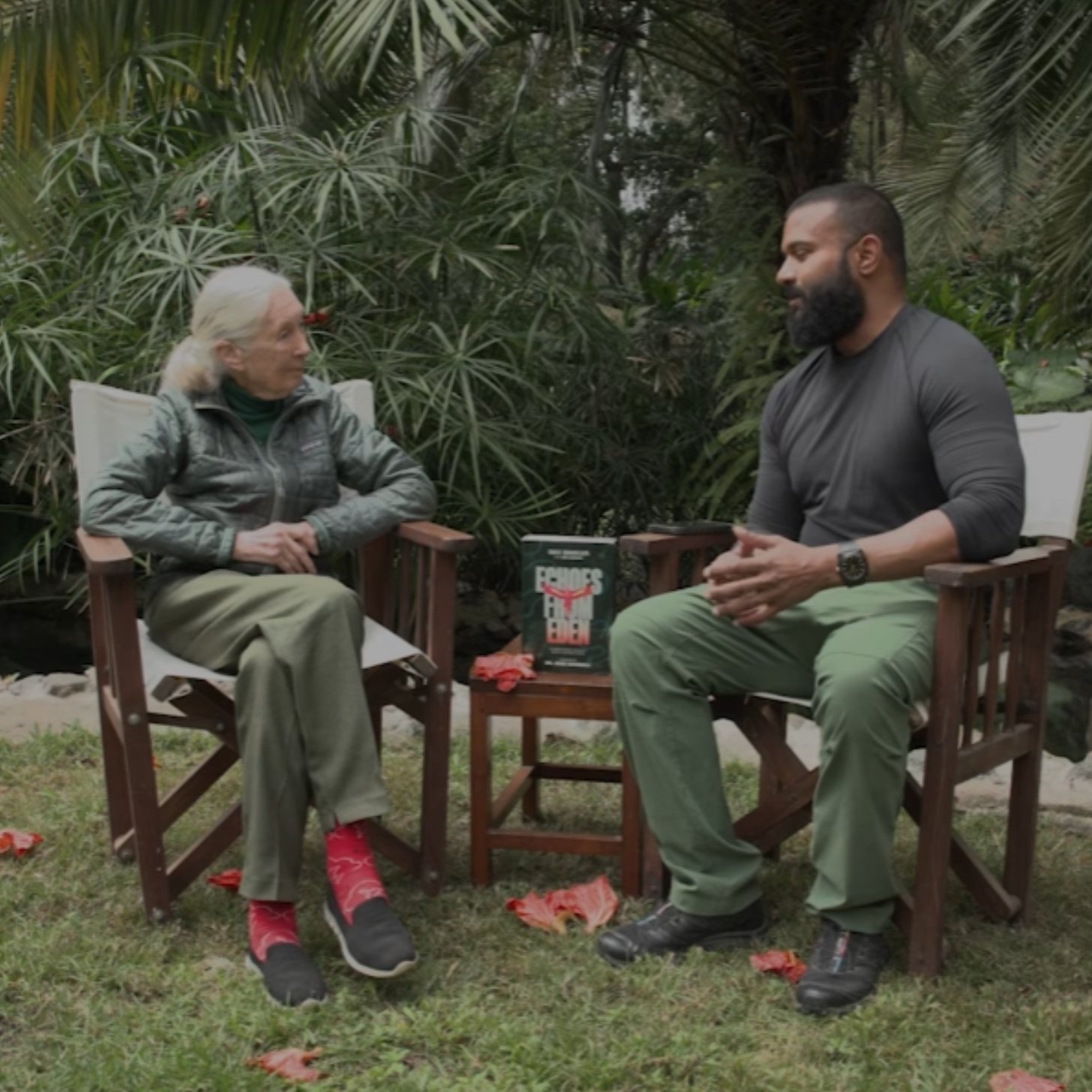 Jane Goodall sits down across from environmentalist Dax Dasilva, a young bearded man of color, as they have a conversation in a lush backyard in Tanzania