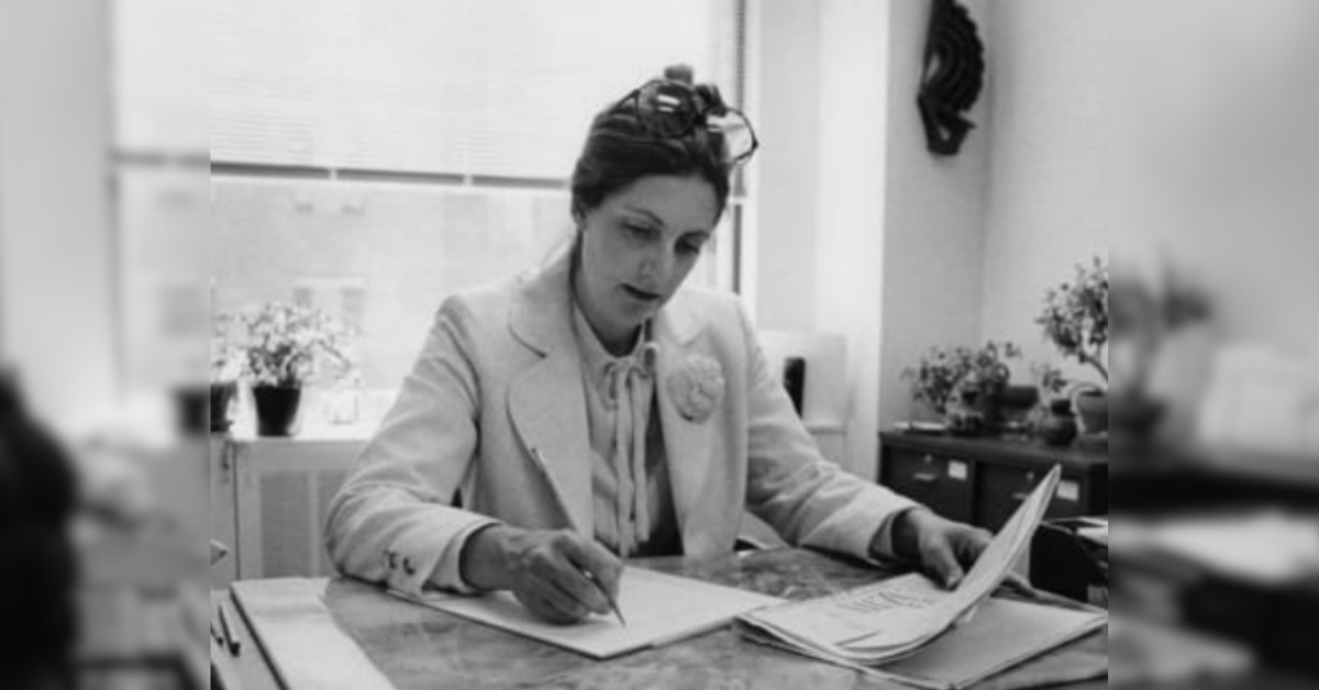 A black-and-white image of a young woman working at a desk.