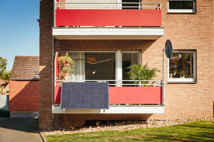 A solar panel hangs from a red balcony