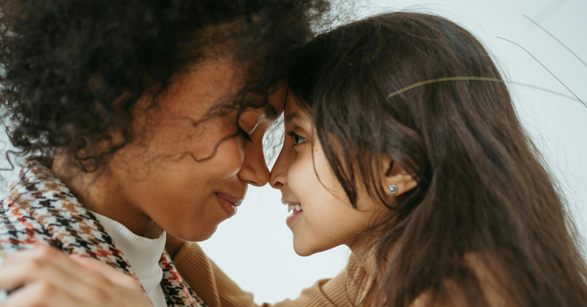 A mother and daughter touch noses in an embrace