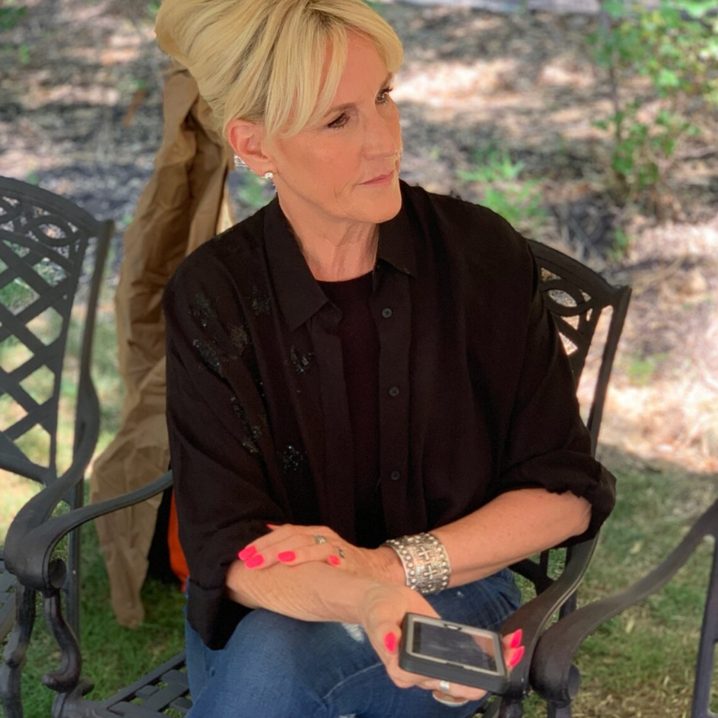 Erin Brockovich in 2019, now a middle-aged woman, still blonde and wearing a pantsuit as she holds out her phone, recording audio for an interview
