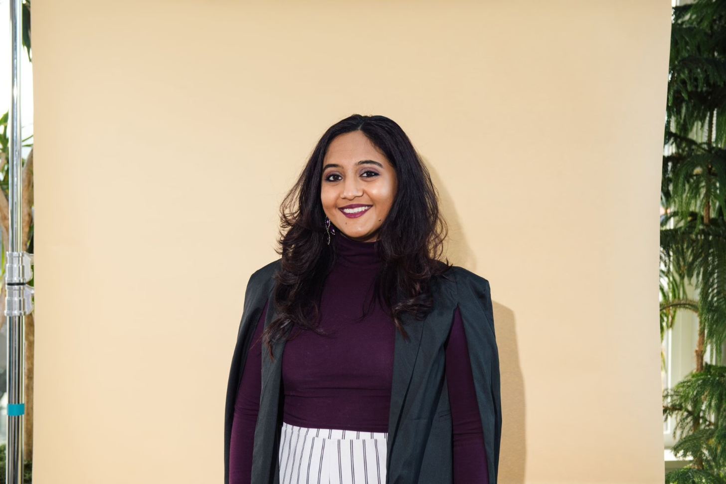Nivi Achanta smiles in front of a tan background