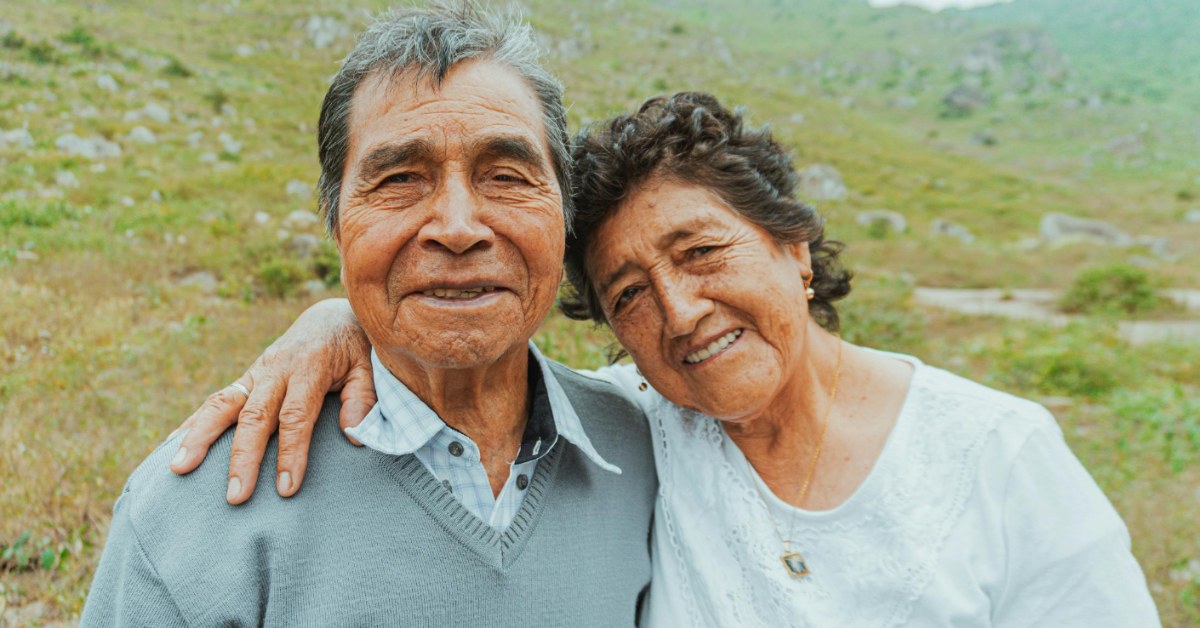 A smiling man and woman, both elderly, in a field