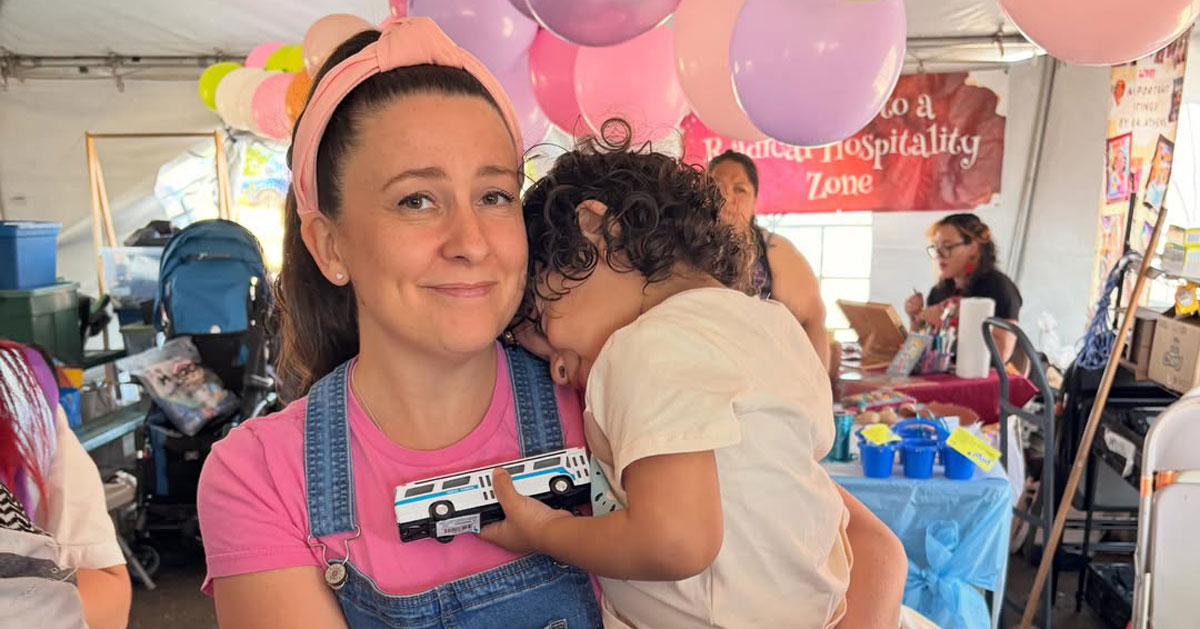 Children's entertainer Ms. Rachel wears her signature pink headband, pink t-shirt, and denim overalls, while hugging a child outside of Delaney Hall Detention Center