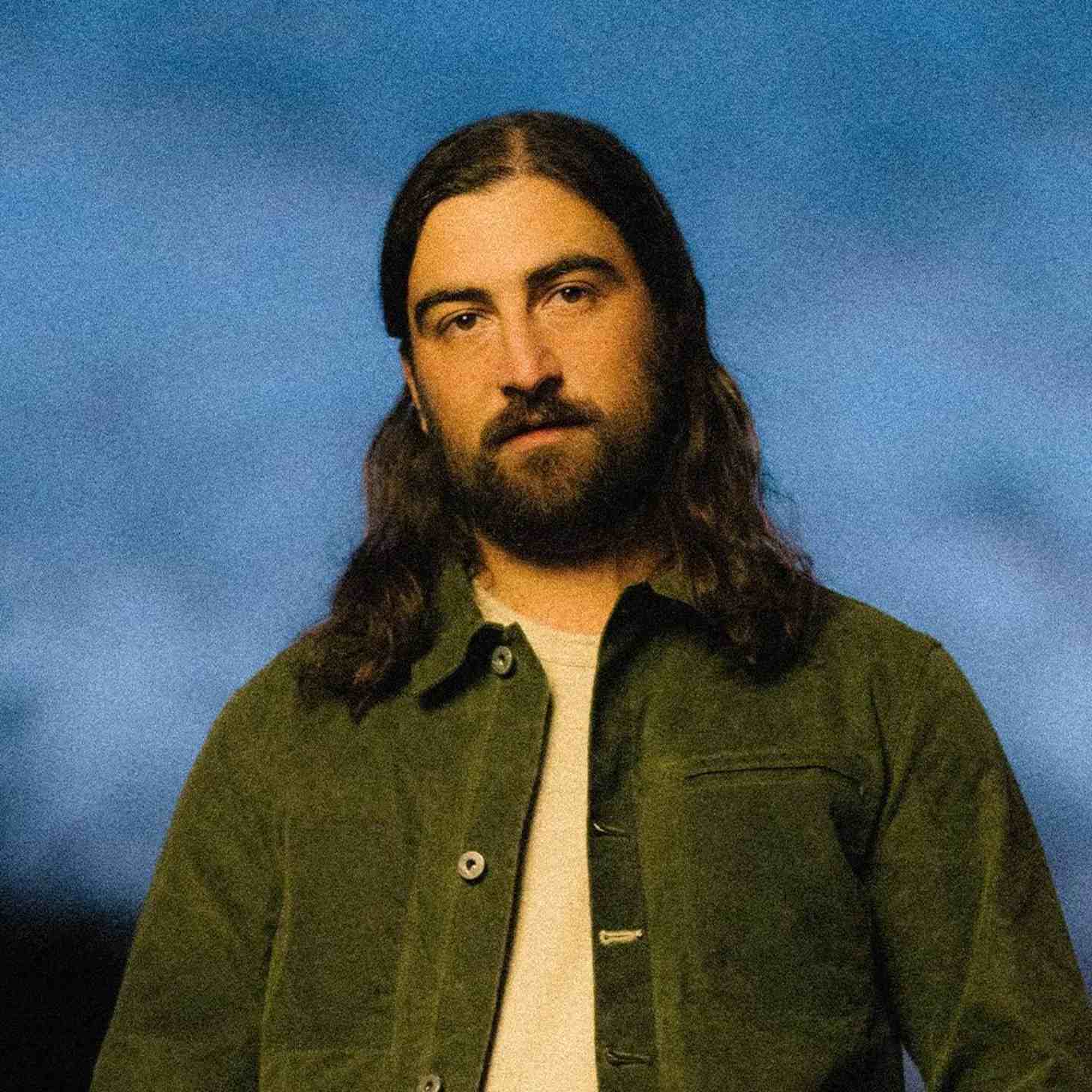 Singer Noah Kahan in front of a blue dusk sky