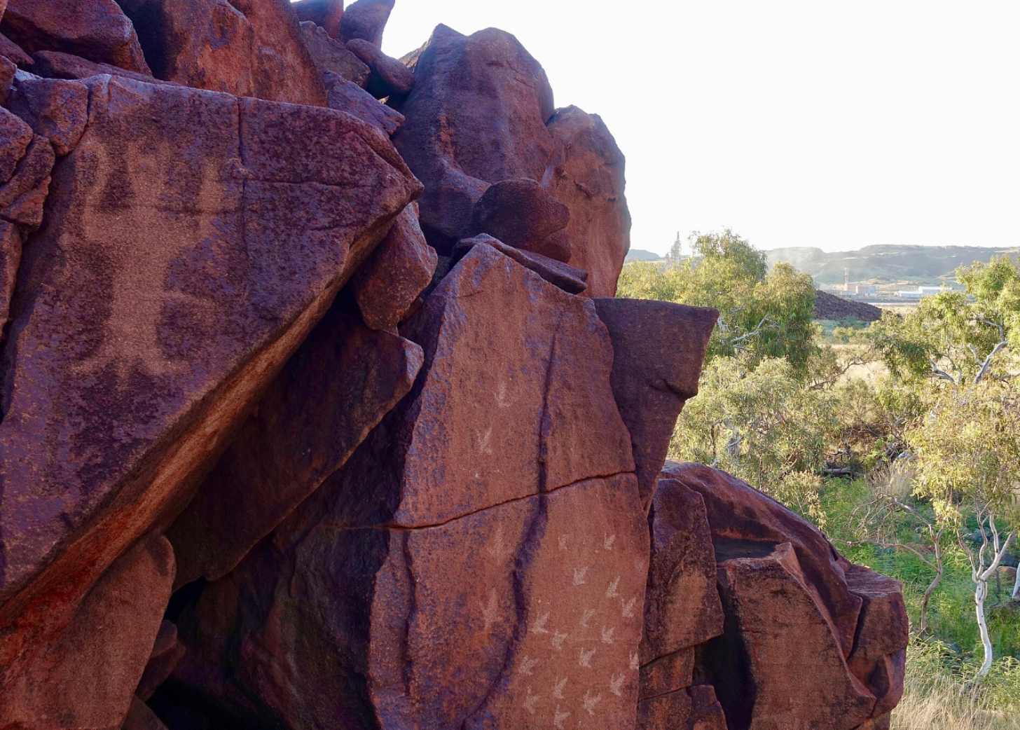 Shapes and symbols carved into red rock faces of a cliff