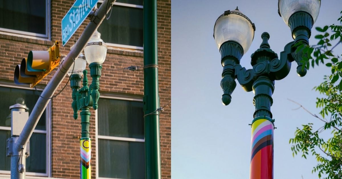 On the left, a street light on a city corner covered in the Intersex-Inclusive Progress Pride Flag. On the right, a separate street light also covered in the same flag. 