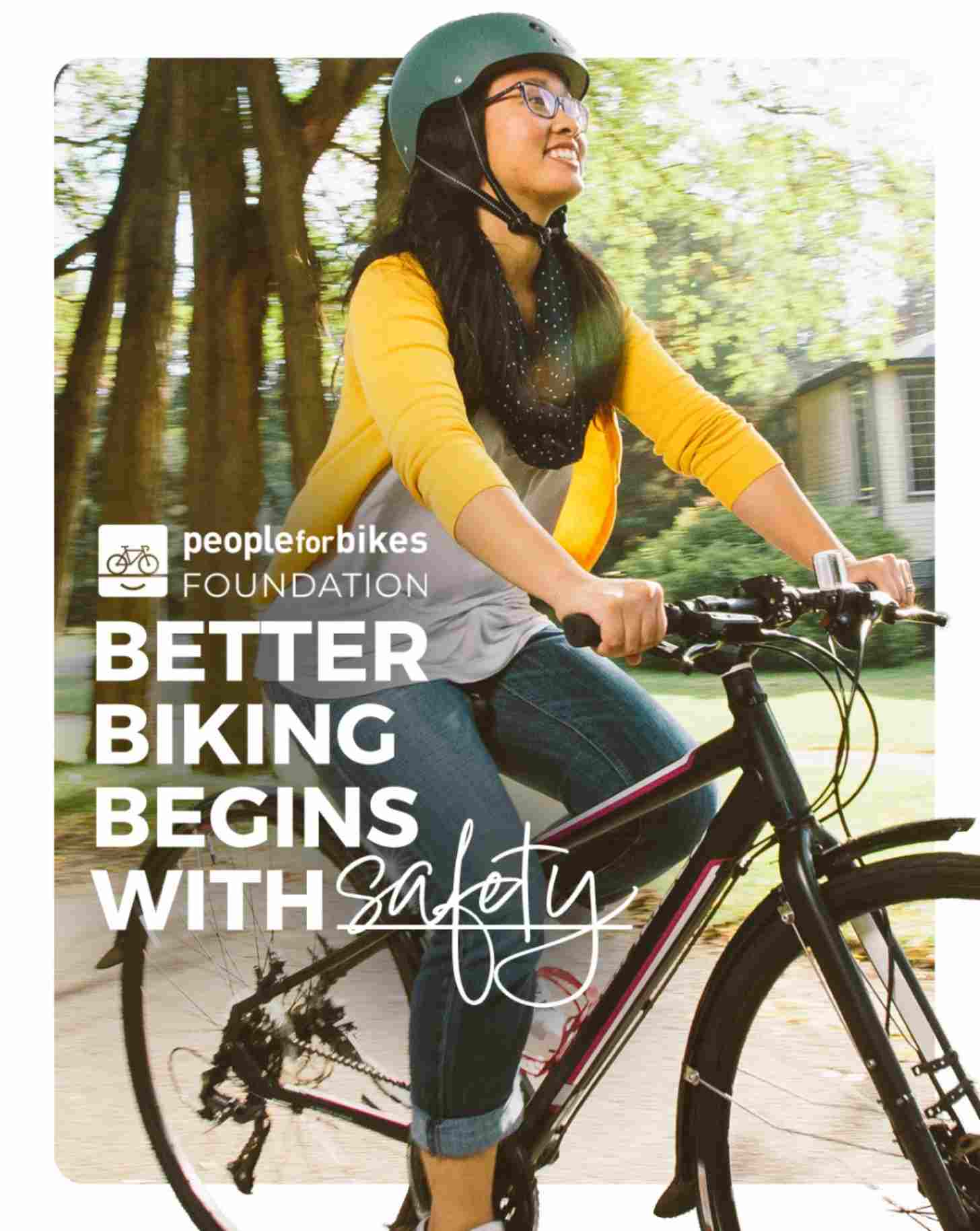 A woman smiles as she rides down a neighborhood street with glasses and a helmet on. The text reads: PeopleForBikes Foundation: Better Biking Begins with Safety