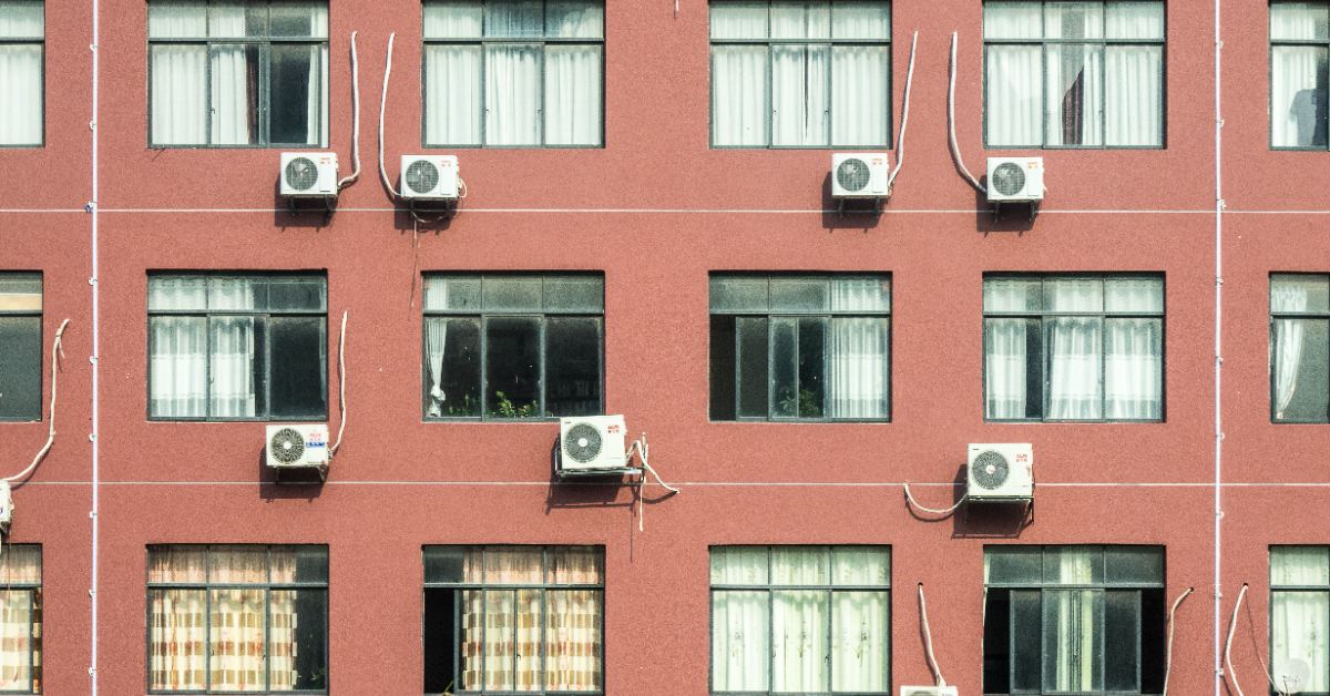 A row of windows and air conditioner units on the side of a red building