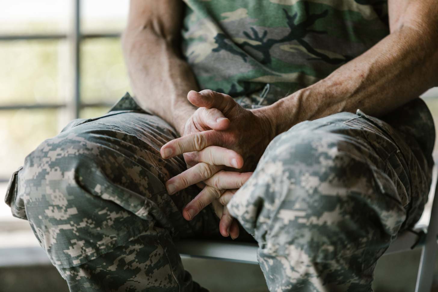 A close-up of a male veteran's hands, sitting in his lap