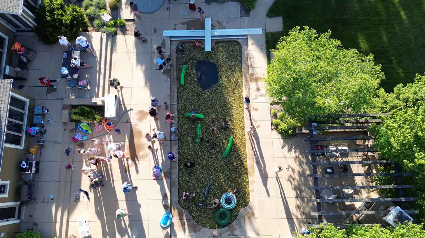 An aerial view of a pool filled with pickles and people swimming inside
