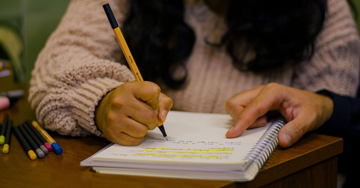 A young person writes in a notebook