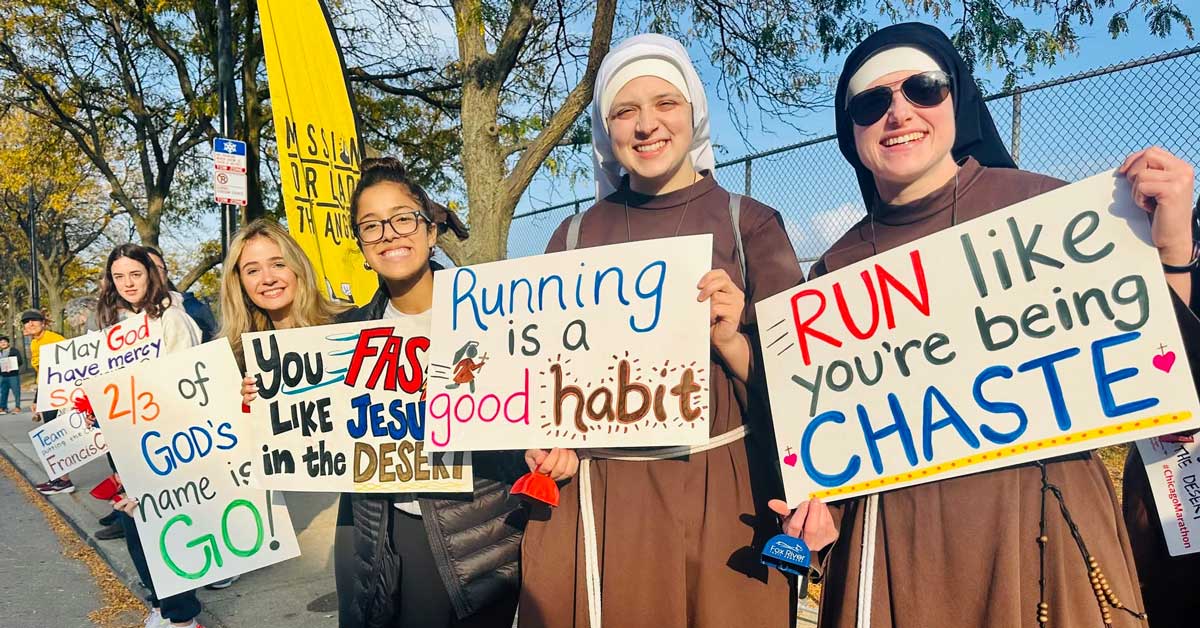 Nuns stand on the sidelines of the Chicago Half Marathon, holding encouraging signs and smiling