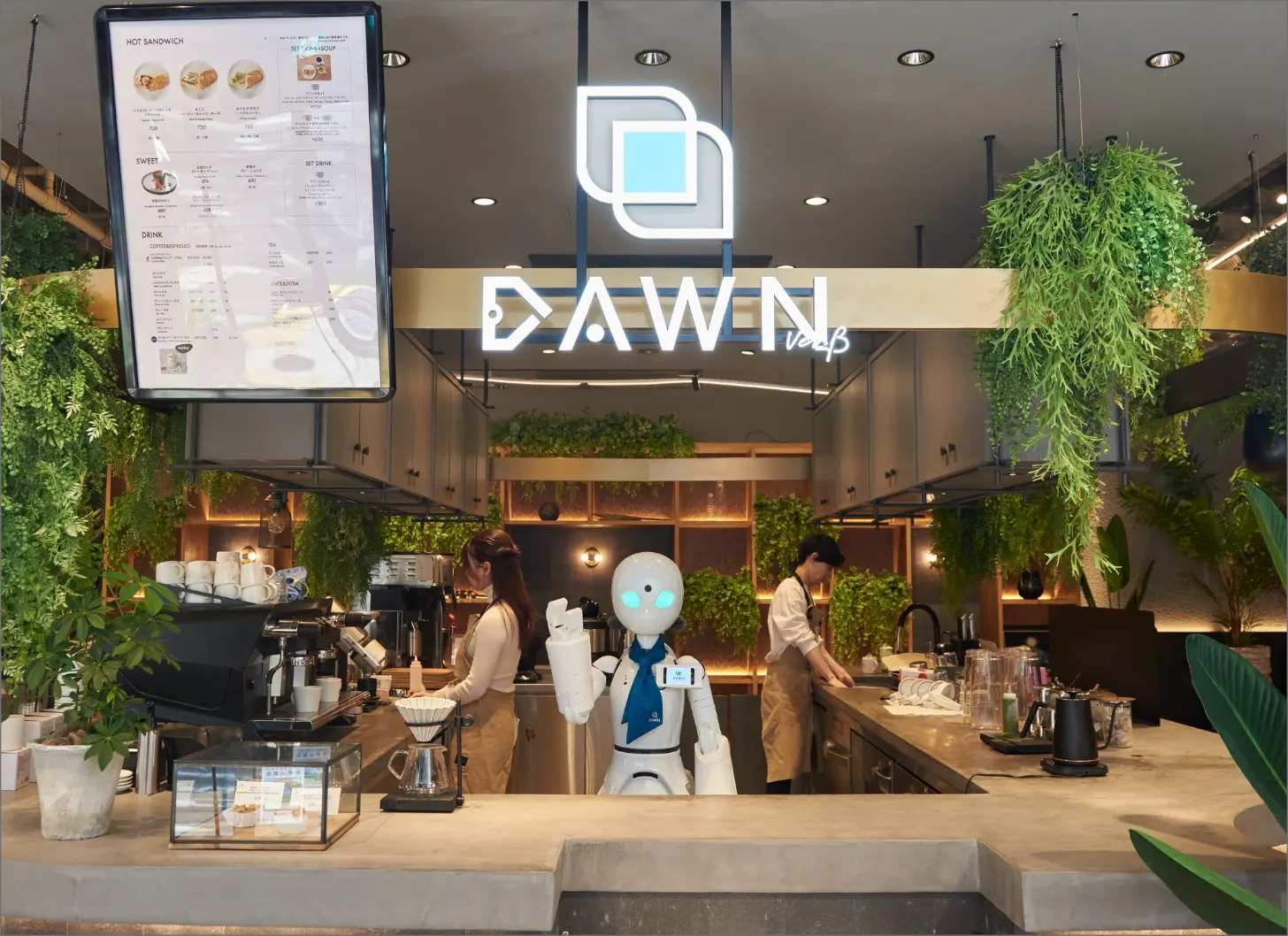 Dawn Cafe storefront with neon signage, service counter with two staff members and a white robot, hanging plants, and a menu board displaying hot sandwich and drink options.