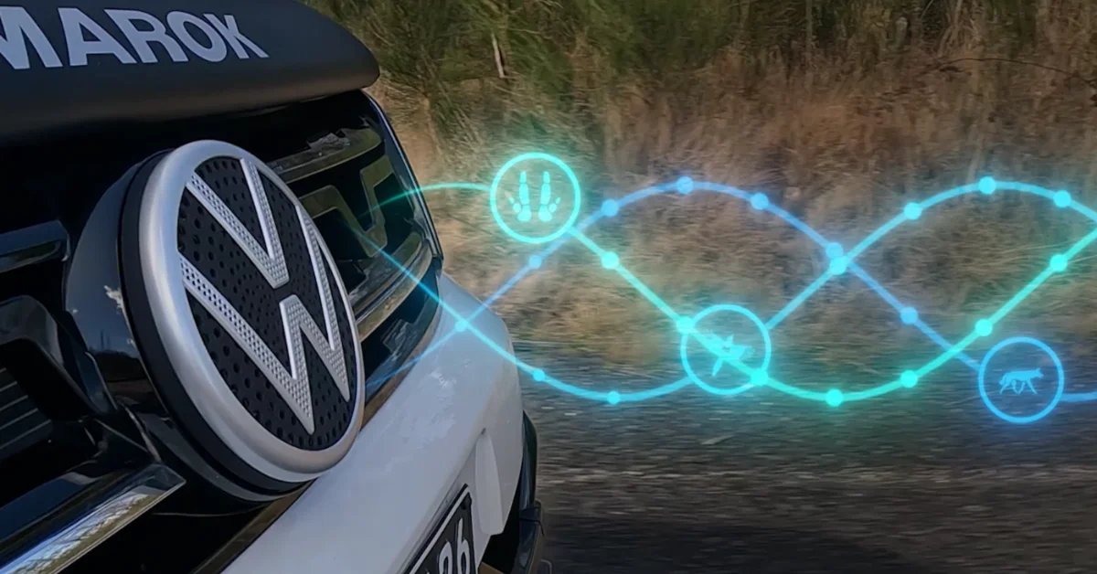 White Volkswagen vehicle with illuminated cyan digital graphics displaying interconnected symbols and icons emanating from the front grille against a forested background.