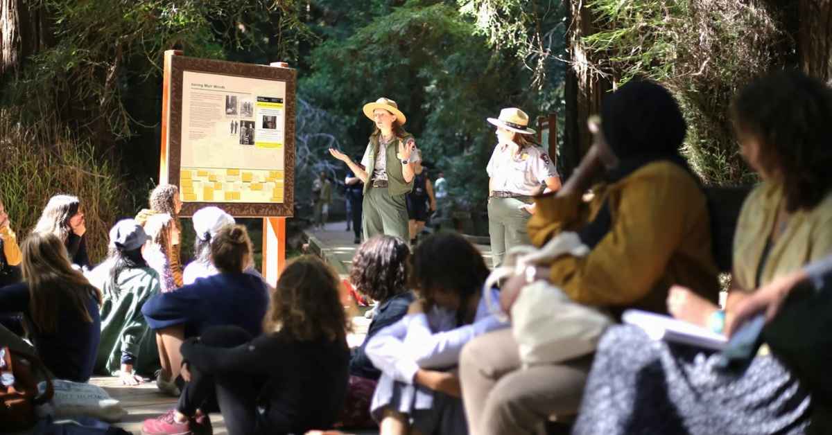Two rangers talk to a group of park visitors.