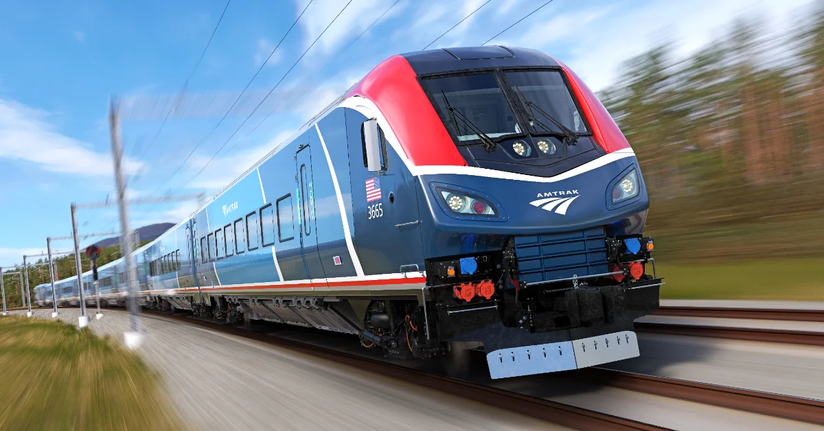 Amtrak passenger train number 3065 with blue, red, and white livery travels on railroad tracks, photographed in motion with blurred surroundings.
