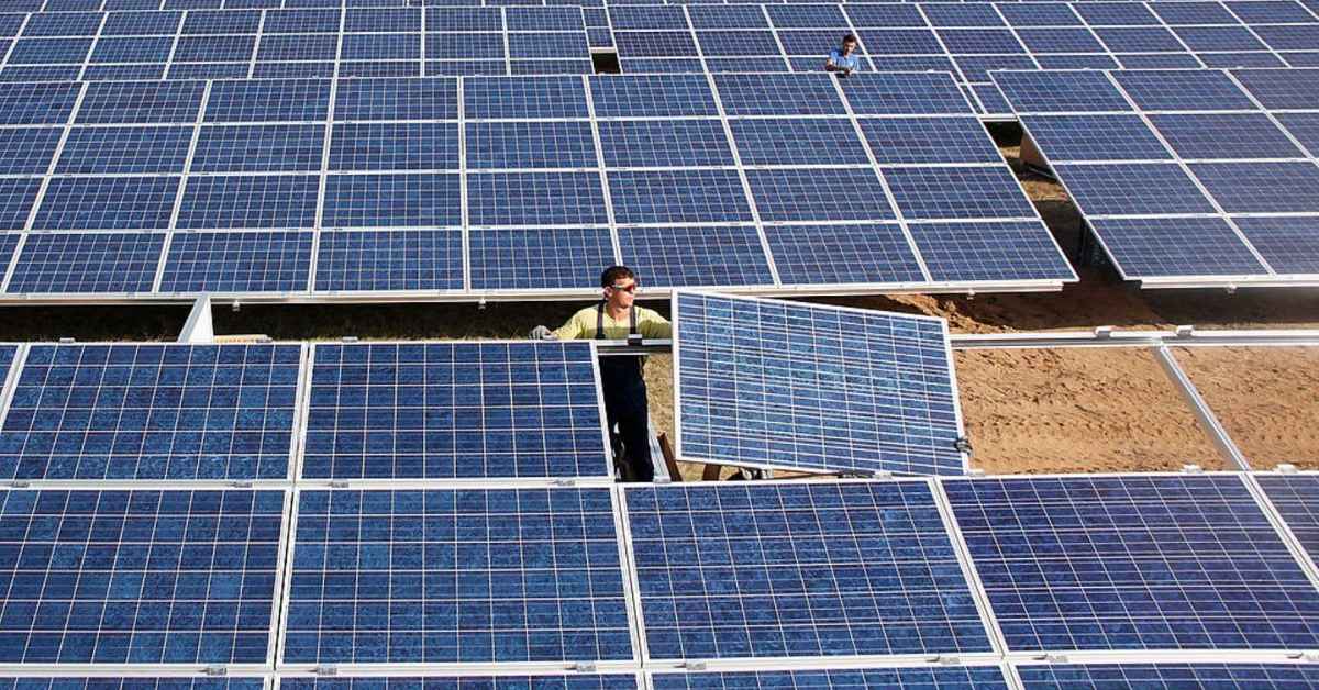 Men at a solar farm, fixing and tending to solar panels