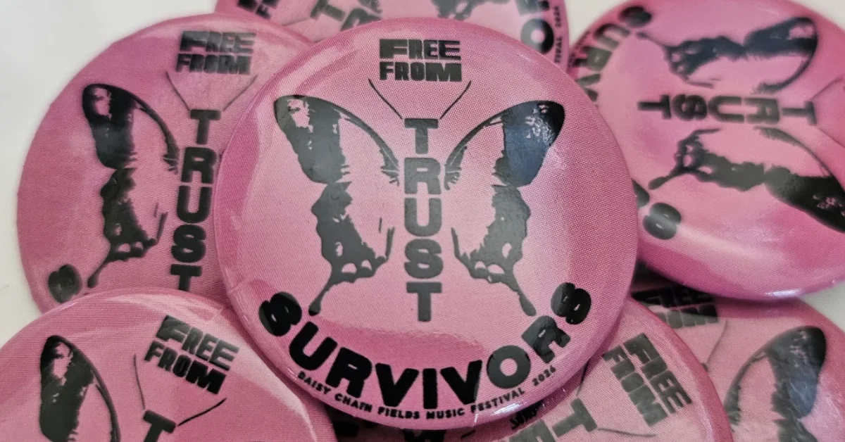 Multiple pink circular badges featuring black butterfly silhouettes and text reading "FREE FROM TRUST" and "SURVIVOR" with "Daisy Chain FIELDS MUSIC FESTIVAL" visible on one badge.