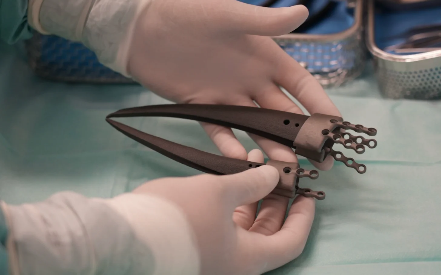 Two hands holding a pair of brown leather scissors with decorative metal handles and dangling ornaments.