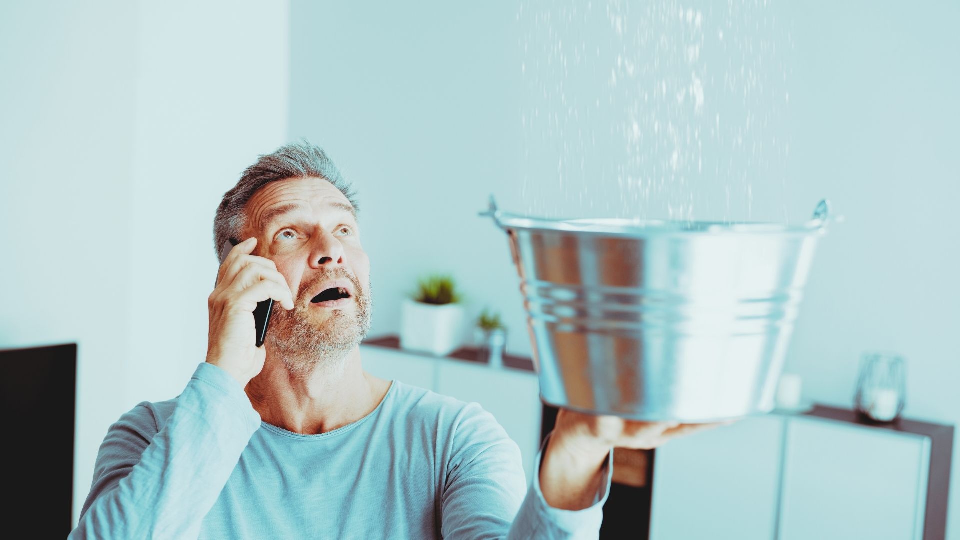 man holding bucket to catch big leak