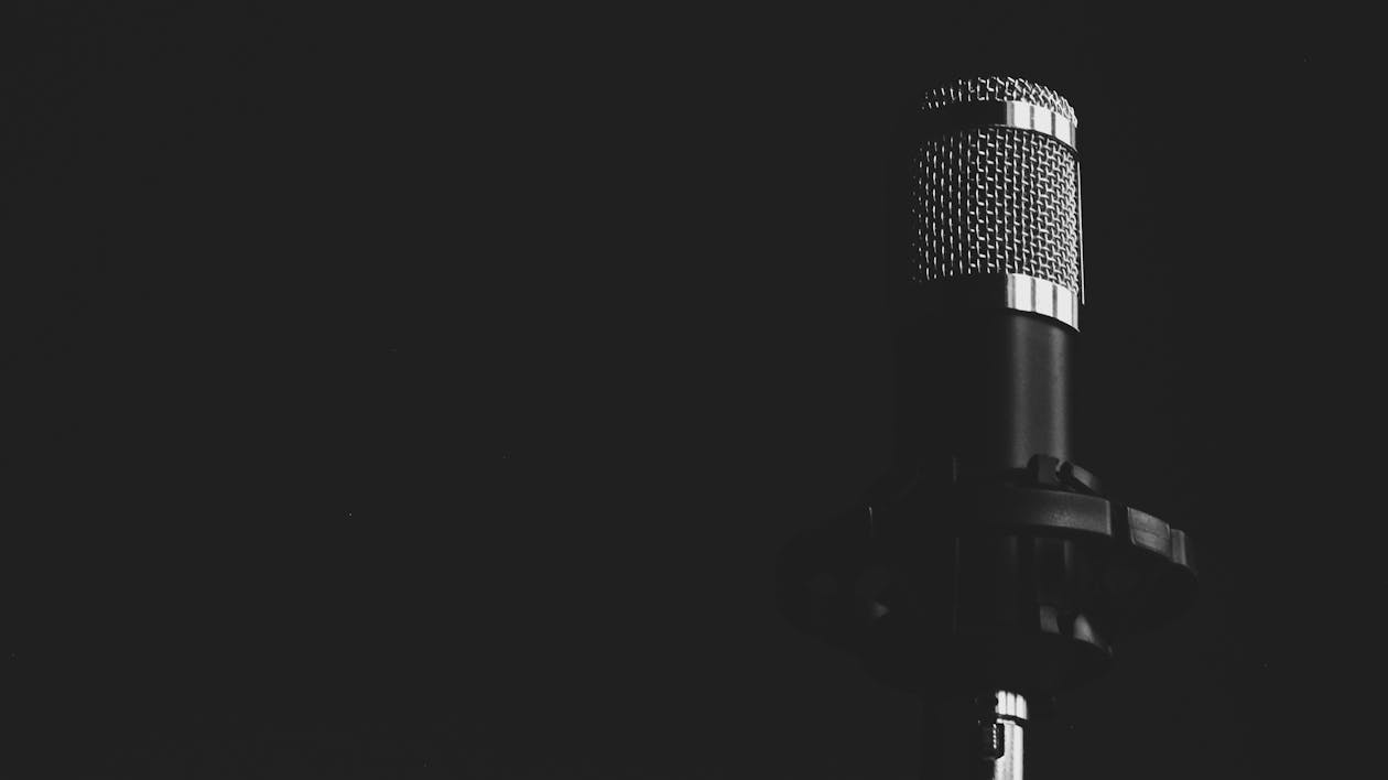 A black and white photo of a vintage microphone on a stand, highlighting its classic design and texture. 