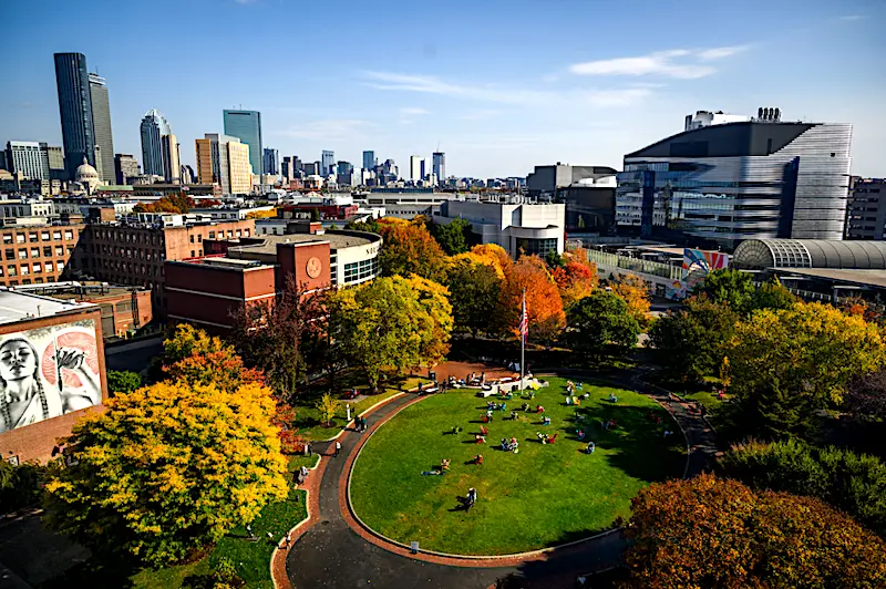 aerial view of Northeastern University's campus with the Boston skyline rising just beyond its red brick buildings