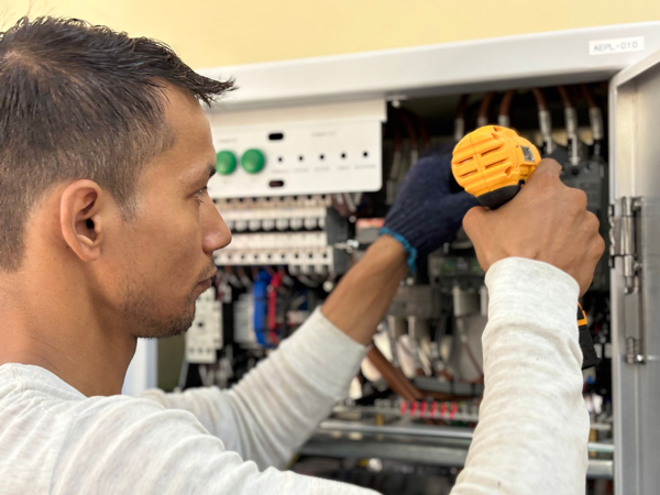 Technician working inside open electrical control panel