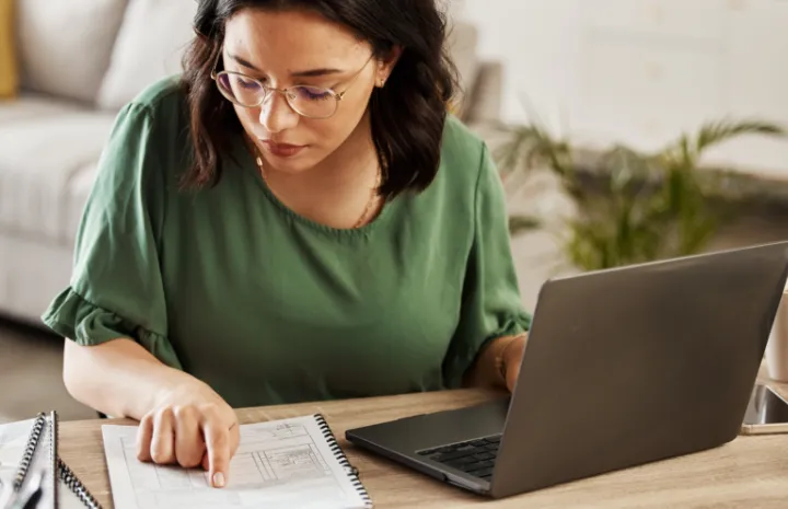 A woman sitting at a table working on a laptop.