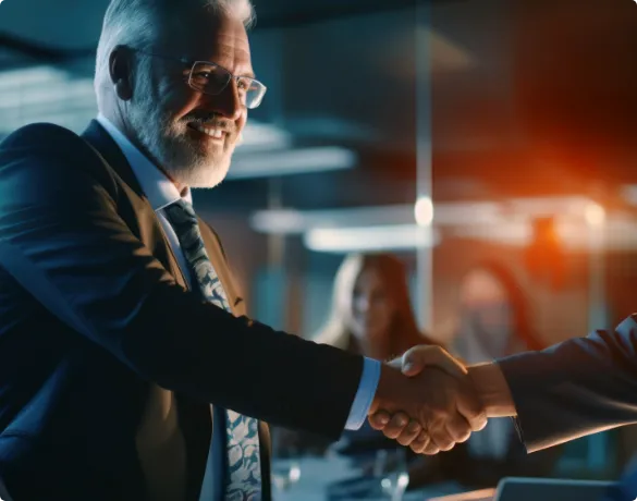 Two men shaking hands in front of a group of people.