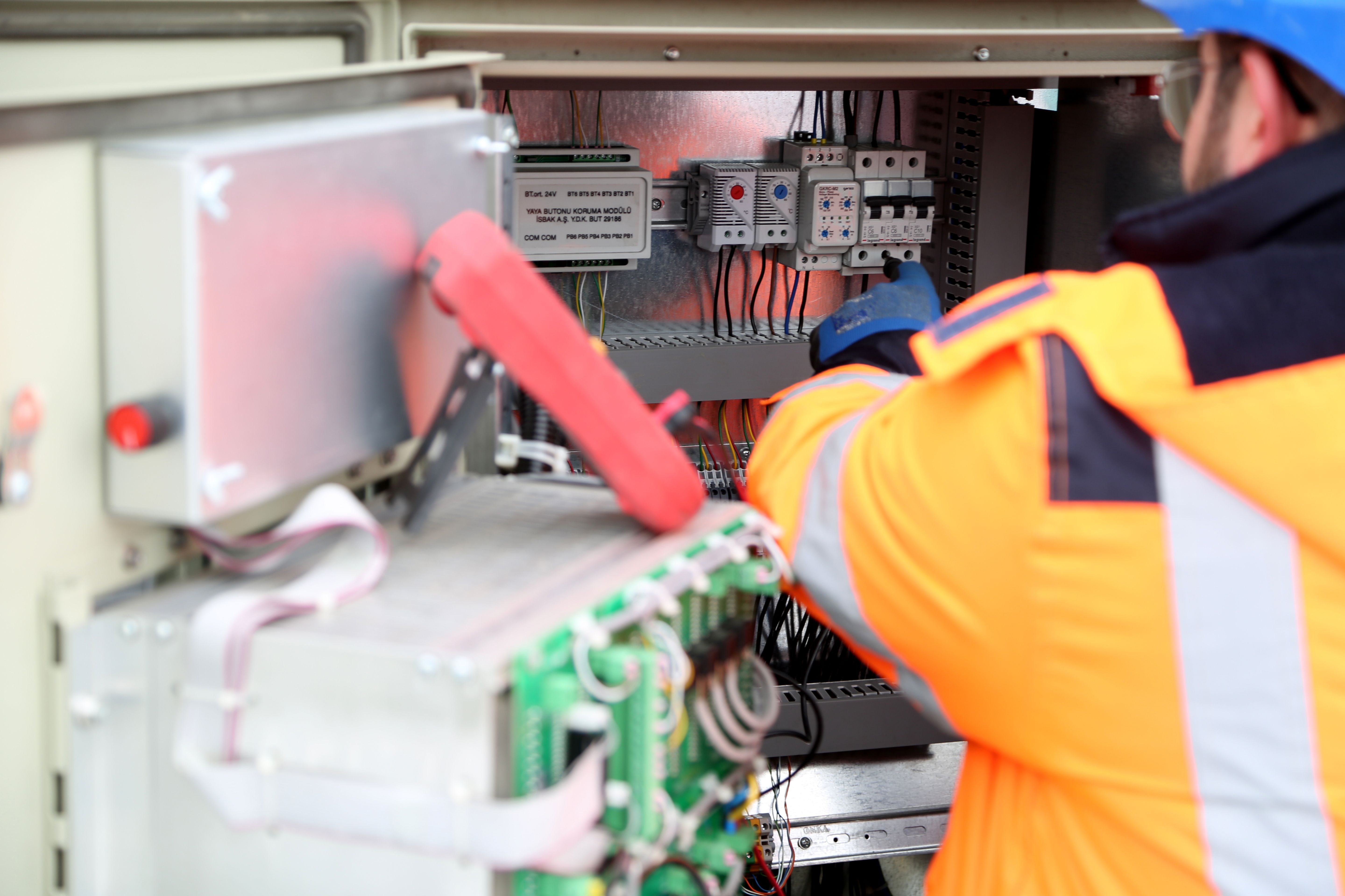Electrician inspecting open electrical control cabinet wiring.