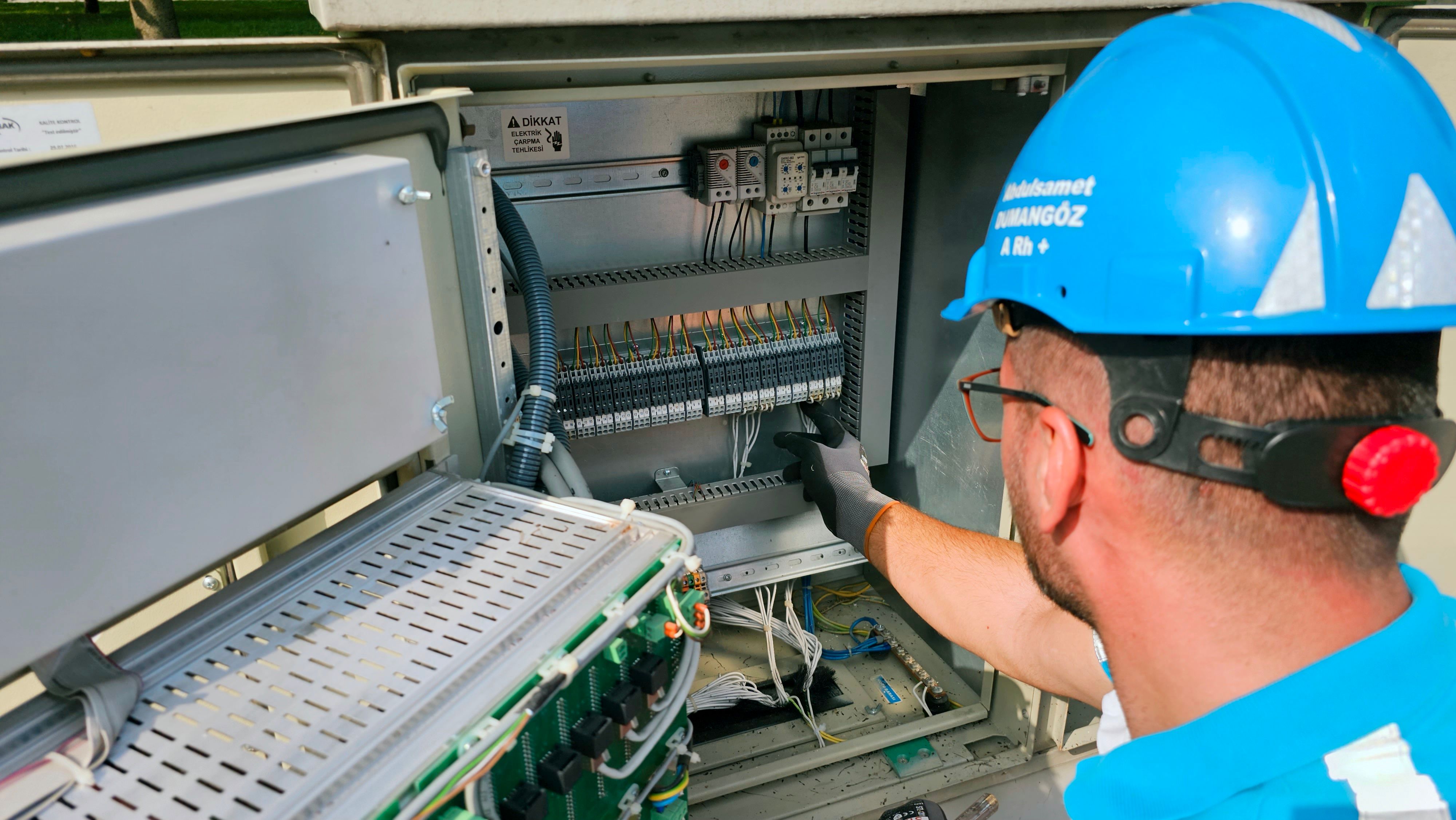 Technician inspecting electrical cabinet wiring and controls.