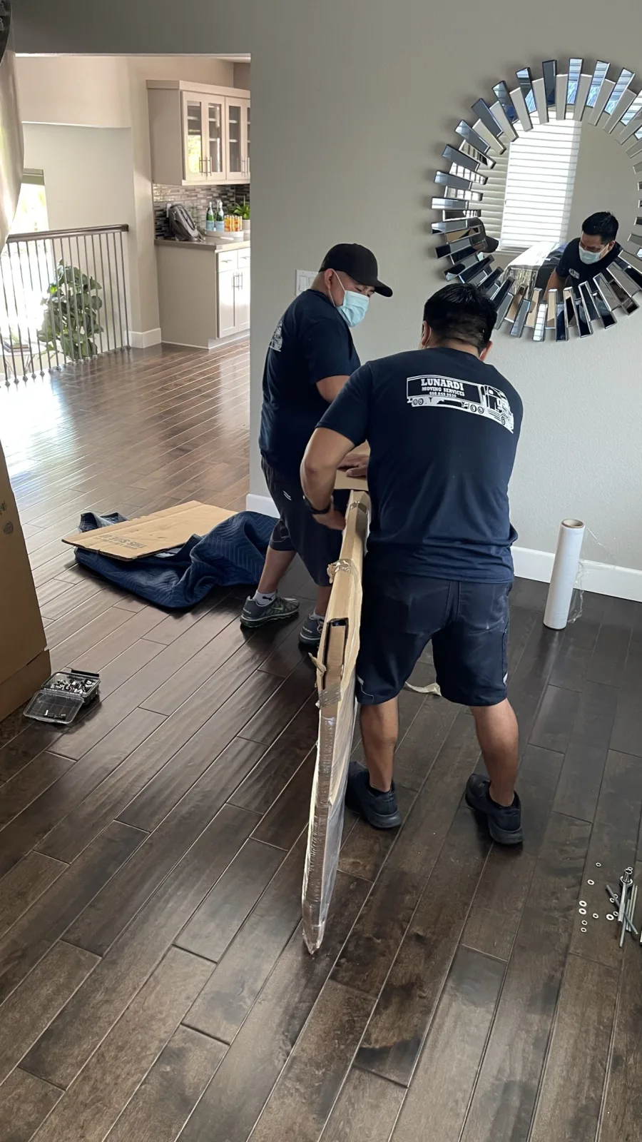 Lunardi Moving crew in branded uniforms shrink wrapping a framed item during a home move
