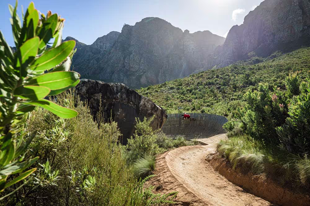 Dirt path winding through lush mountainous landscape with rocky peaks