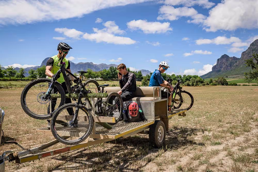 Mountain bikers with bicycles on trailer in scenic rural landscape