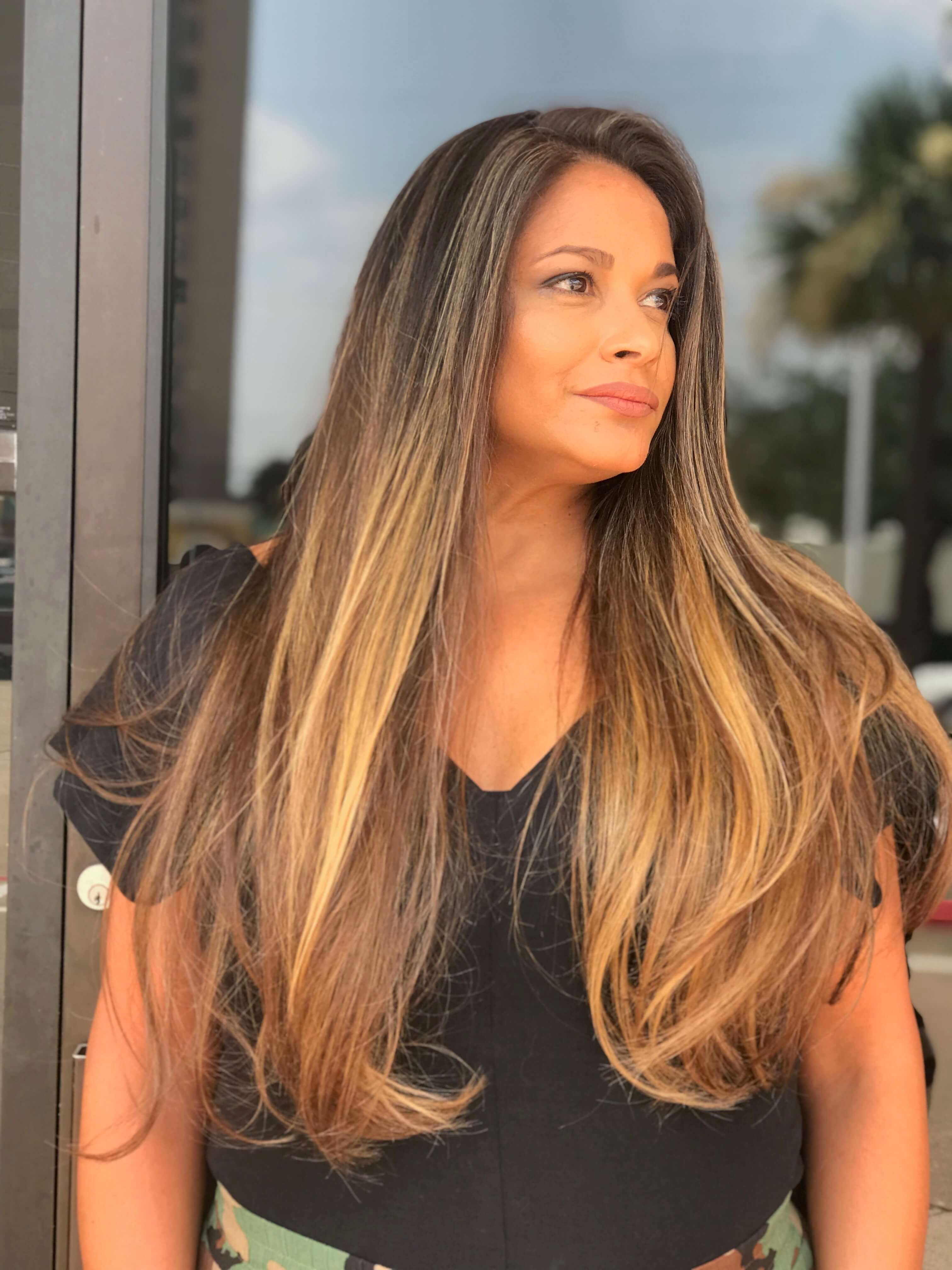 Long layered brunette hair with sun-kissed caramel balayage by Janelle Alexis Salon in Houston