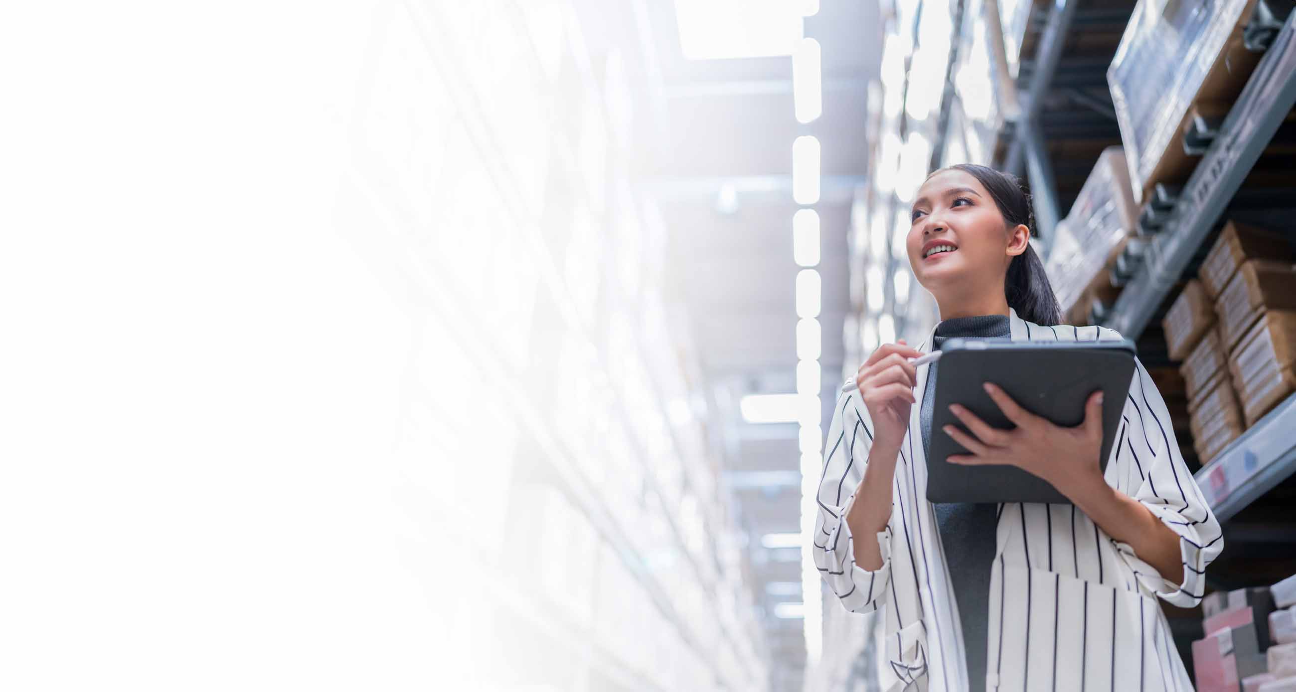 Asian lady with tablet computer taking inventory in a large warehouse