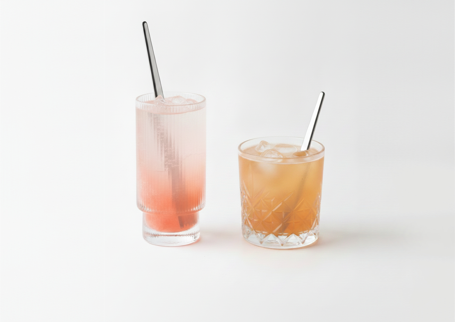 A tall and a short cocktail glass next to each other with stirrers in them.