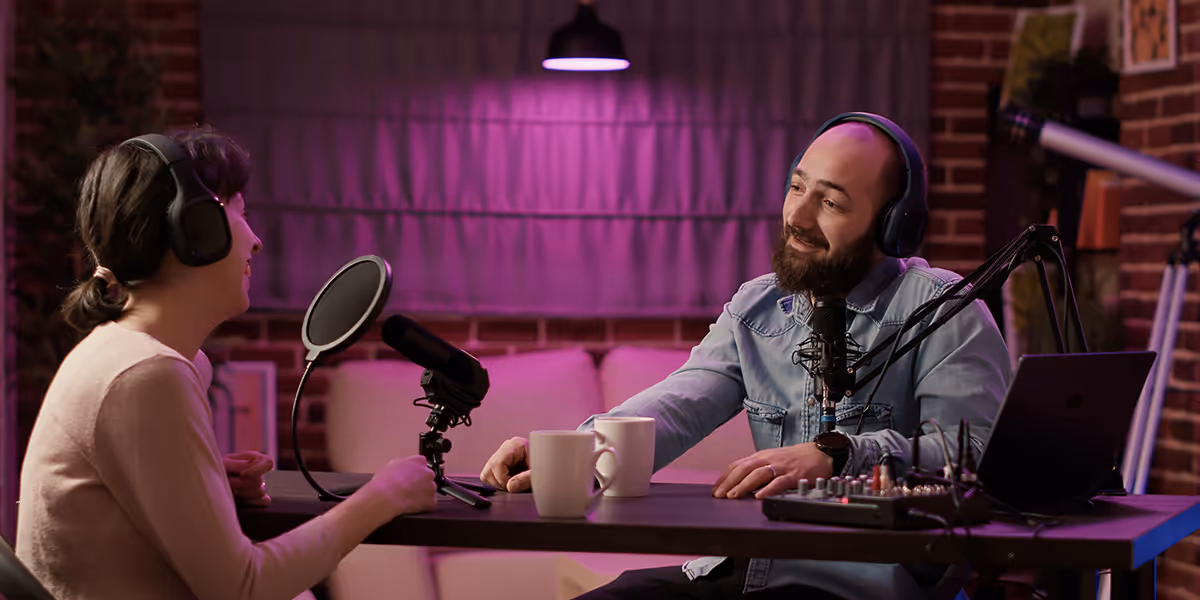 male and female sitting across each other and talking through microphones
