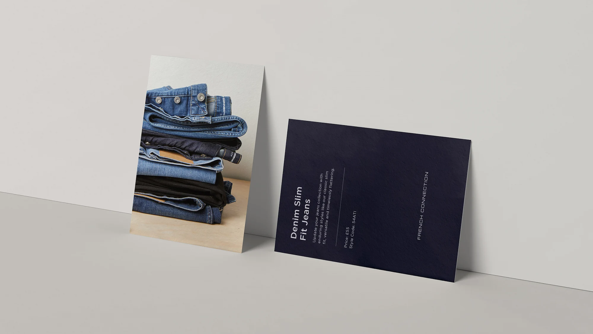 Two cards leaning on a wall: one stacked denim jeans, the other shows Denim Slim Fit Jeans text.