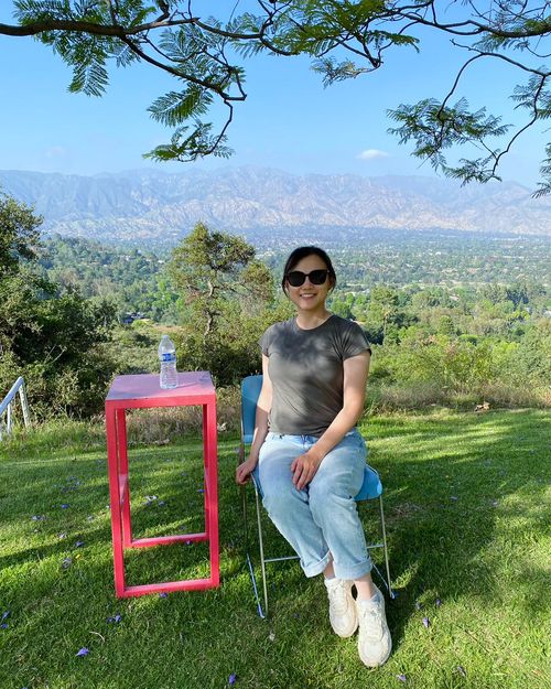 A picture of Julia Han sitting on a chair with a mountain backdrop