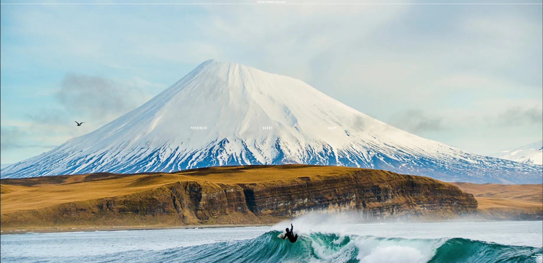 Photo of man surfing in front of snowy mountain by Chris Burkard